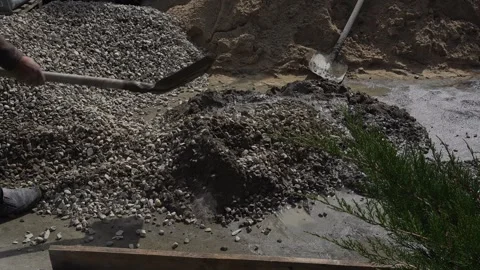 A worker prepares a concrete mixture with a shovel Stock Footage 307384470