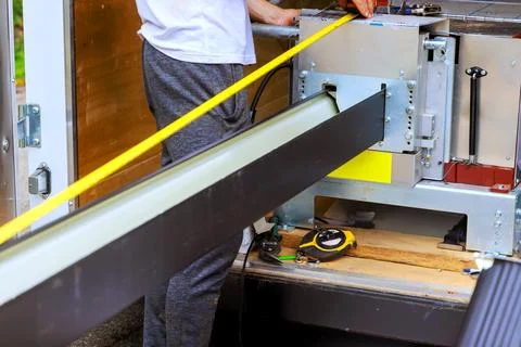 Worker prepares equipment for gutter system using tape measure tools at job site Stock Photos
