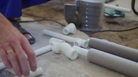 Worker prepares insulated plastic pipes and fittings on floor Stock Footage 312475141