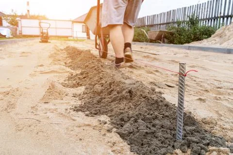 A worker prepares a platform for laying paving slabs in the defocus. Stock Photos