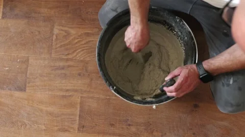 Worker preparing gypsum plaster mortar in bucket on floor Stock Footage 339298369