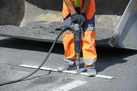 Worker preparing lay for asphalting the road using pneumatic road breaker, st Stock Photos