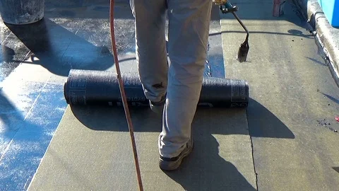 Worker preparing part of bitumen roofing felt roll for melting by gas heater 動画素材 86660310