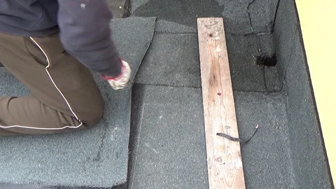 Worker preparing part of bitumen roofing felt roll for melting by gas heater Stock Footage 107337711