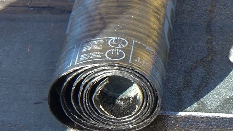 Worker preparing part of bitumen roofing felt roll for melting by gas heater 스톡 동영상 112347516