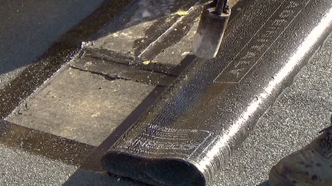 Worker preparing part of bitumen roofing felt roll for melting by gas heater 스톡 동영상 113446135