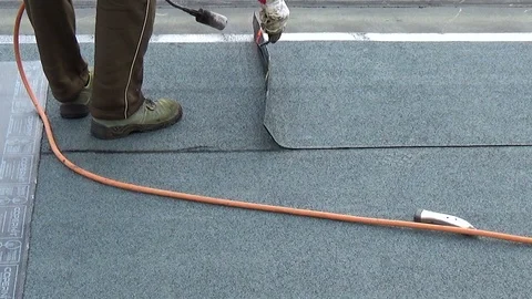 Worker preparing part of bitumen roofing felt roll for melting by gas heater Stock-Footage 119791975