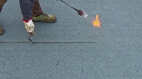 Worker preparing part of bitumen roofing felt roll for melting by gas heater  Vídeo Stock 293081174