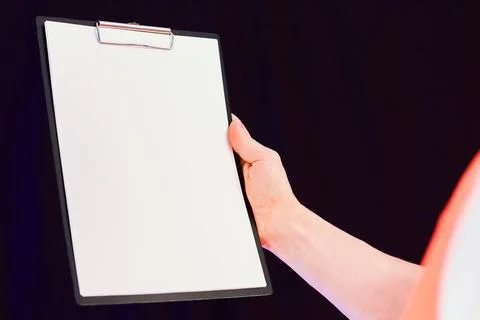 Worker presenting blank clipboard at angle on dark isolated background Stock Photos