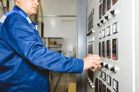 A worker presses a button and starts an automatic manufacturing process in a Stock Photos