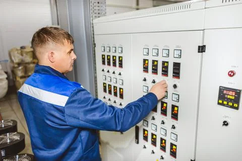 A worker presses a button and starts an automatic manufacturing process in a Stock Photos