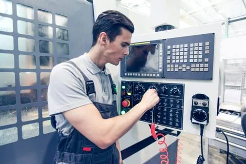 Worker pressing buttons on CNC machine Stock Photos