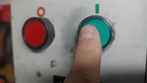 Worker pressing a green start button and then a red stop button on a machine con Stock Footage 335646451