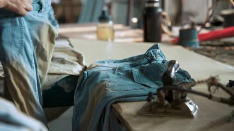 Worker Pressing Jeans Seams using Heavy Industrial Steam Iron at Factory China Stock Footage 335609738