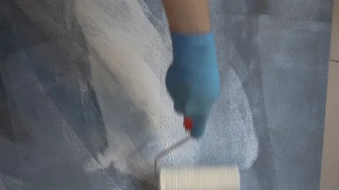 Worker primes a black surface with a roller. white stains on a dark wall Vídeos de archivo 157439282