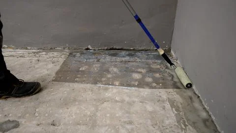 Worker Priming Concrete Floor with Roller Stock-Fotos