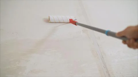 Worker priming with a paint roller. Primer worker with paint roller. white pr Stock Photos
