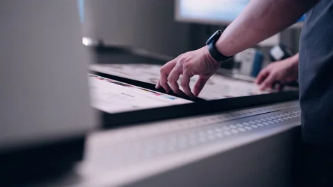 A worker in the printing house checks the quality of the printed packaging. Stock Footage 197463216