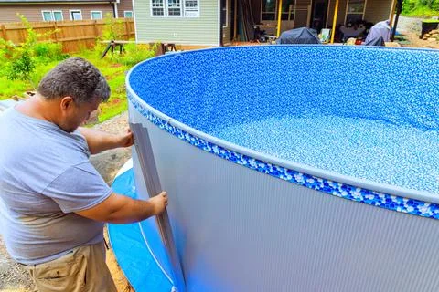 Worker is in a process of installing metal frame of an above ground pool Stock Photos