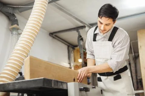 Worker processes board on woodworking machine Stock Photos