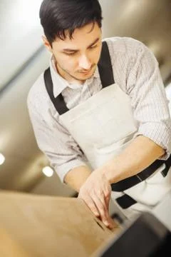 Worker processes board on woodworking machine Stock Photos