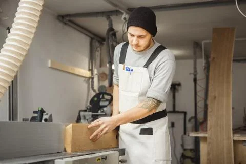 Worker processes board on woodworking machine Stock Photos
