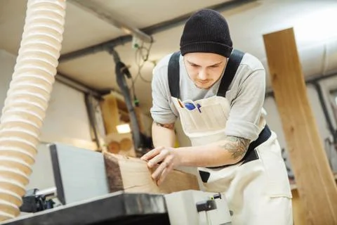 Worker processes board on woodworking machine Stock Photos