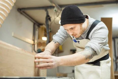 Worker processes board on woodworking machine Stock Photos