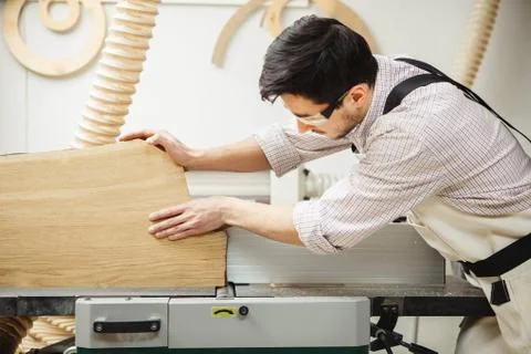 Worker processes board on woodworking machine Stock Photos