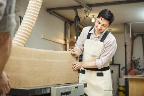 Worker processes board on woodworking machine Stock Photos