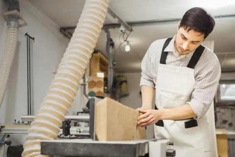 Worker processes board on woodworking machine Stock Photos