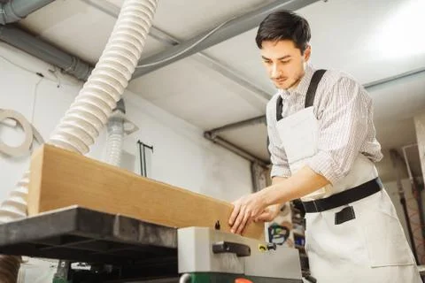 Worker processes board on woodworking machine Stock Photos