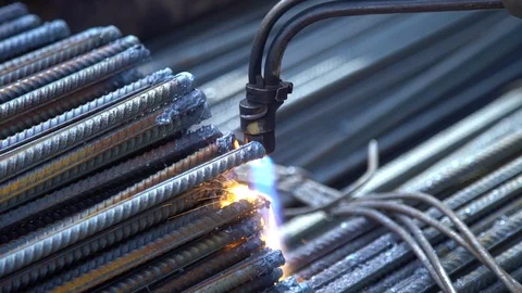 Worker processes the edges of metal pins with a flame of a welding machine at Stock Footage 113563386
