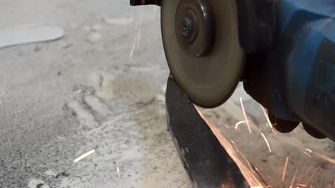 A worker processes a piece of metal that is clamped in a vice with a circular sa Stock Footage 156285277