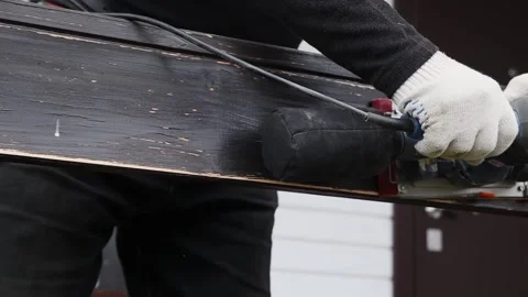 A worker processes the side surface of a wooden railing with a vibrating sander 스톡 동영상 144731626