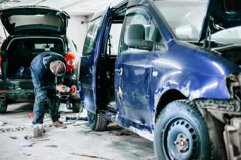 Worker processes the surface of the car door Stock Photos