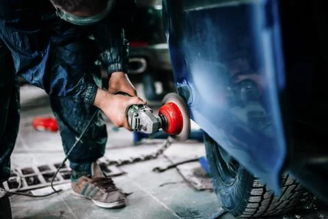 Worker processes the surface of the car door Stock Photos