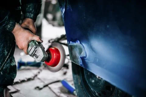 Worker processes the surface of the car door Stock Photos