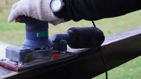 A worker processes the upper surface of a wooden railing with a vibrating sander Vídeo Stock 143083946