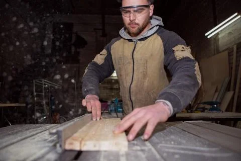 Worker processes a wooden Board on a circular machine Stock Photos