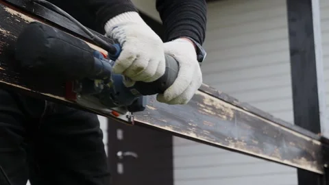 A worker processes a wooden railing with a vibration sander near the house Vídeos de archivo 142703238