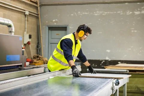 Worker processing wood panel on production line Stock Photos