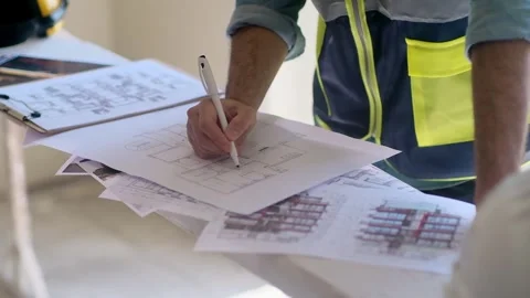 Worker in professional uniform editing and correcting construction documentation Stock Footage 249614142