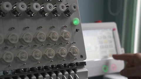 A worker is programming a sewing machine with a CNC using a tablet computer. The 库存影片 119237914