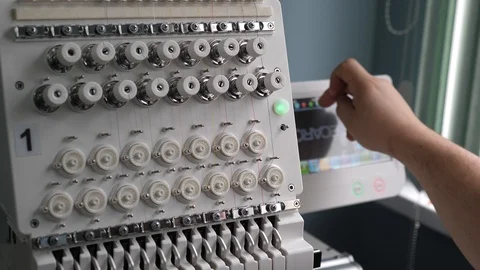 A worker is programming a sewing machine with a CNC using a tablet computer. The 库存影片 119237961