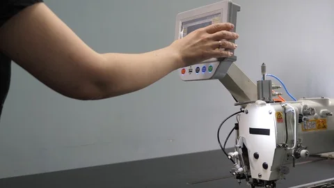 A worker is programming a sewing machine with a CNC using a tablet computer. The 库存影片 119238040
