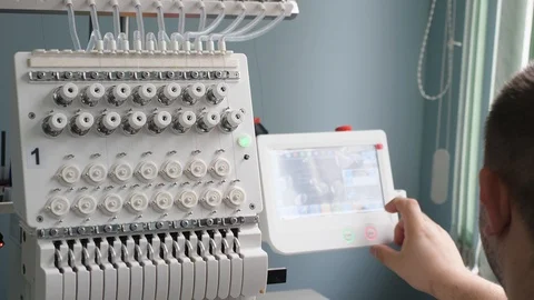 Worker is programming a sewing machine with a CNC using a tablet computer. The 库存影片 119607913