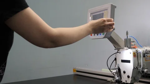 Worker is programming a sewing machine with a CNC using a tablet computer. The 库存影片 119607986