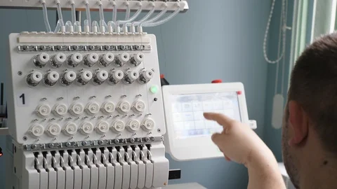 Worker is programming a sewing machine with a CNC using a tablet computer. The 库存影片 119608060