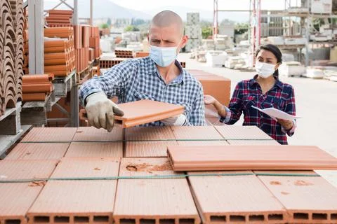Worker in protecrive mask stacking bricks in warehouse of materials Stock Photos